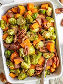 White dish filled with roasted brussels sprouts and sweet potatoes.