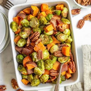 White dish filled with roasted brussels sprouts and sweet potatoes.
