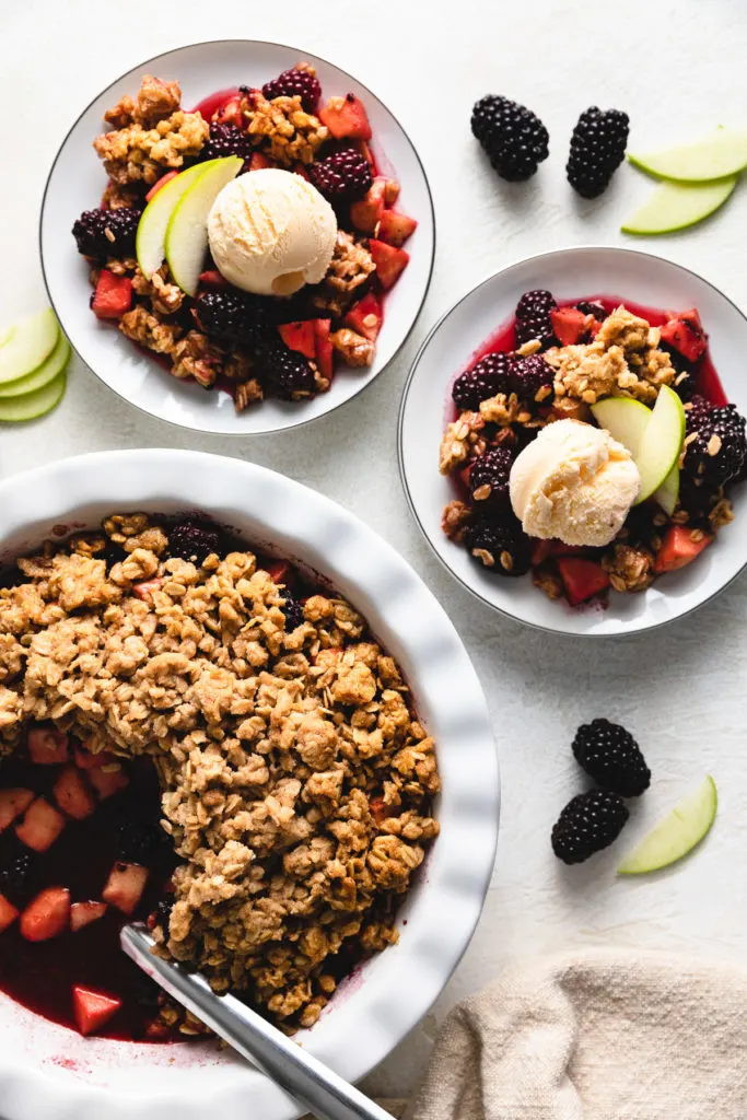 Top down view of plates of apple and blackberry crumble.