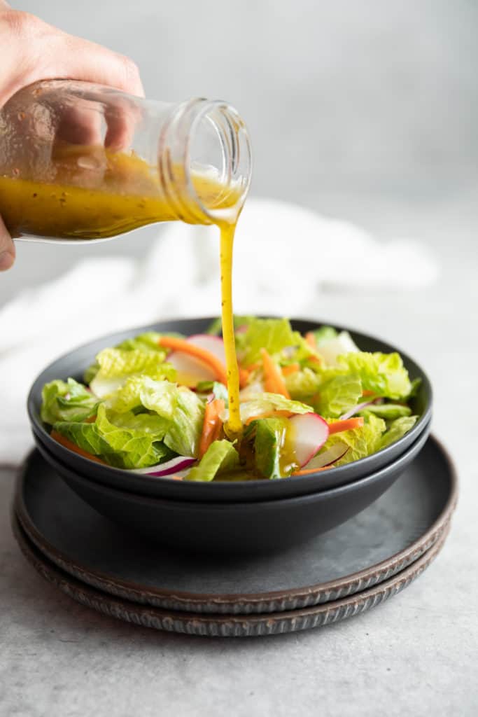 Dressing being poured onto a salad.
