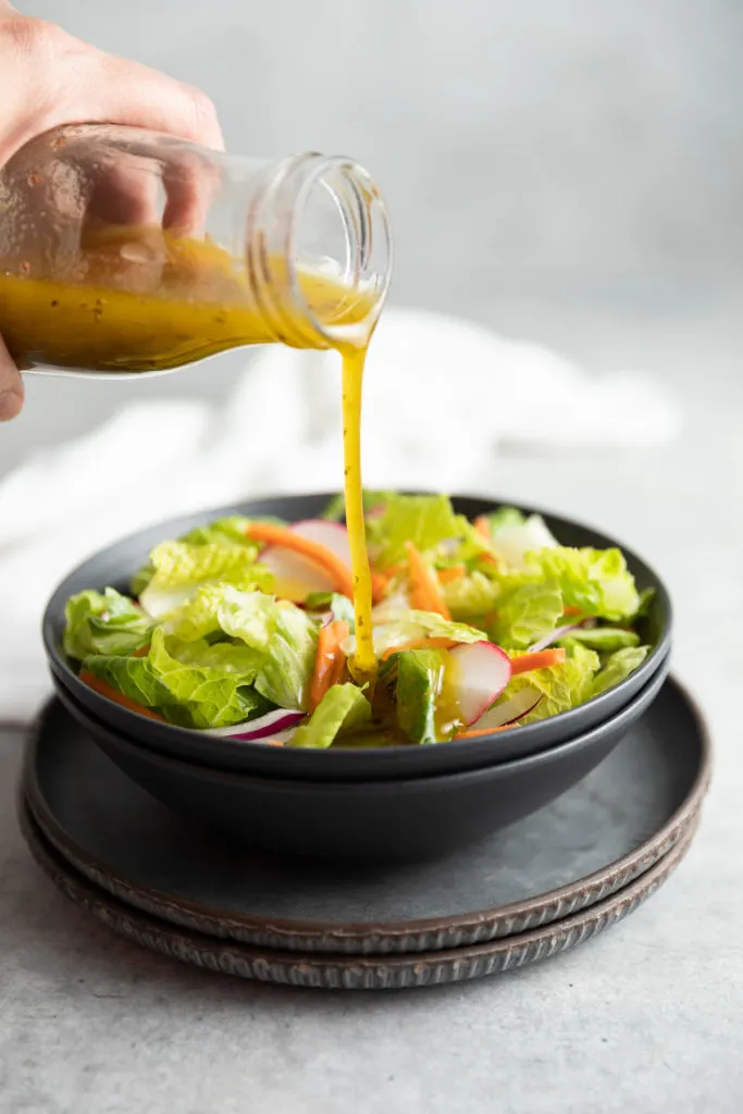 Dressing being poured onto a salad.