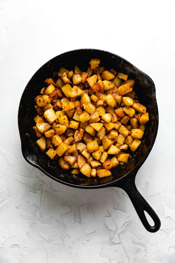 Breakfast potatoes in a cast iron pan.