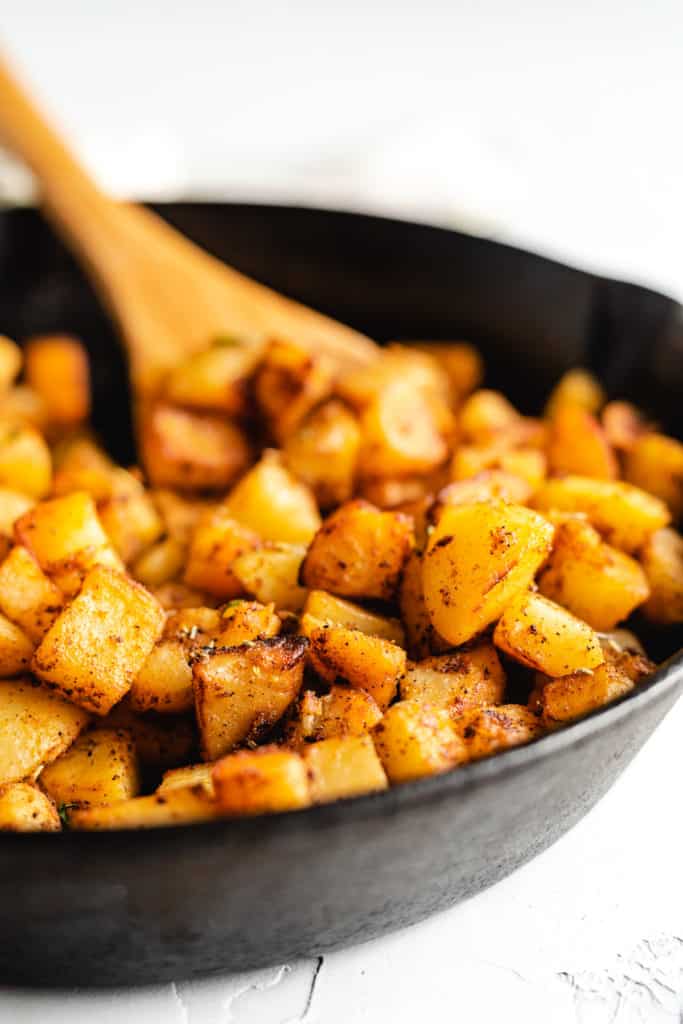 Wooden spoon in a pan of potatoes.