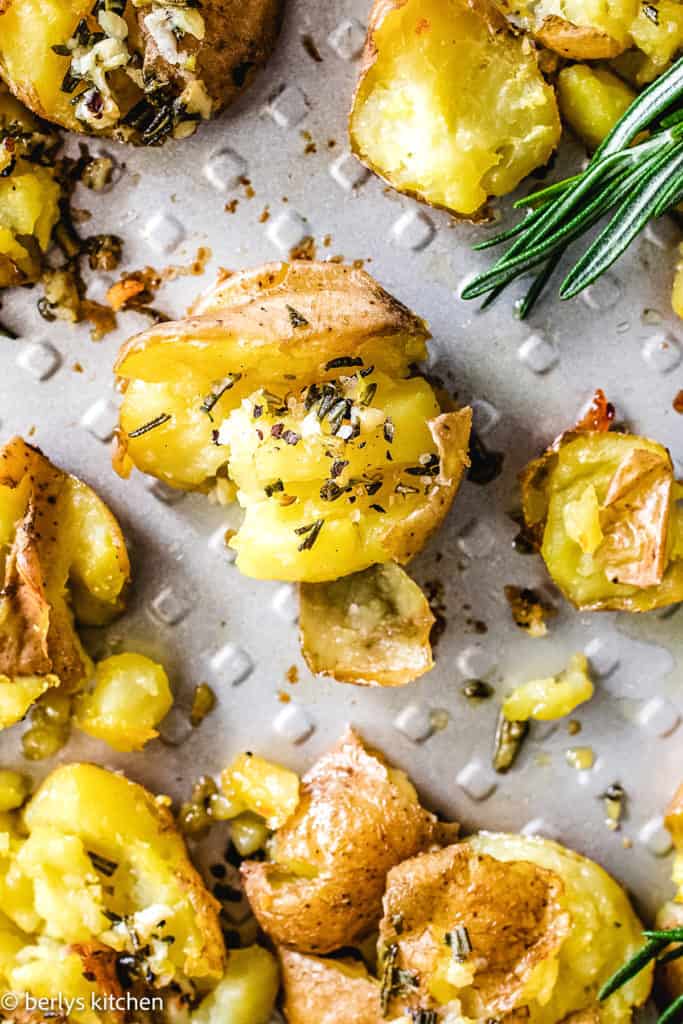 Top down view of smashed potatoes on a pan.