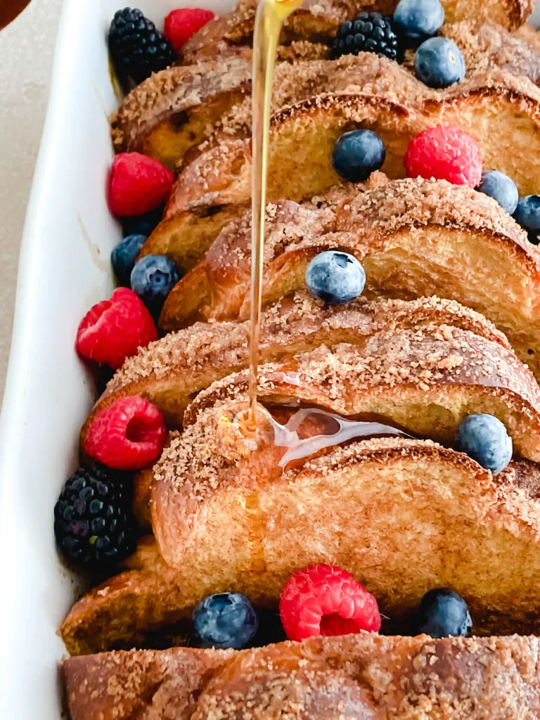 Maple syrup being drizzled over baked french toast.