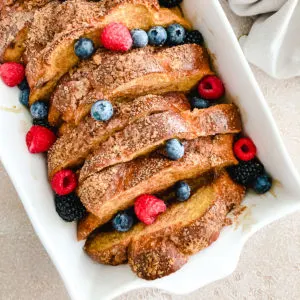 Close up view oven baked toast and fruit in a baking dish.