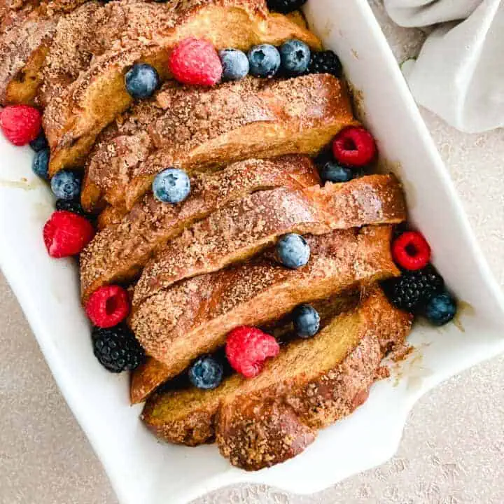 Close up view oven baked toast and fruit in a baking dish.