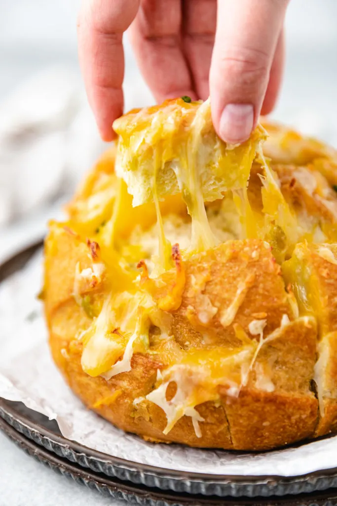 Piece of bread being removed from pull apart bread.