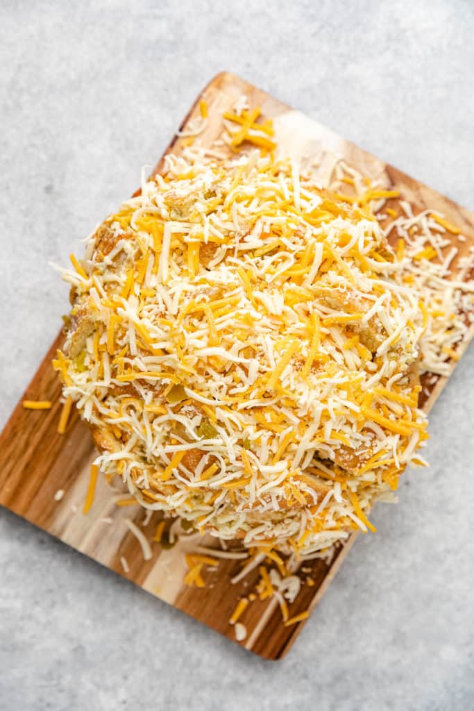Shredded cheese on top of a loaf of bread.