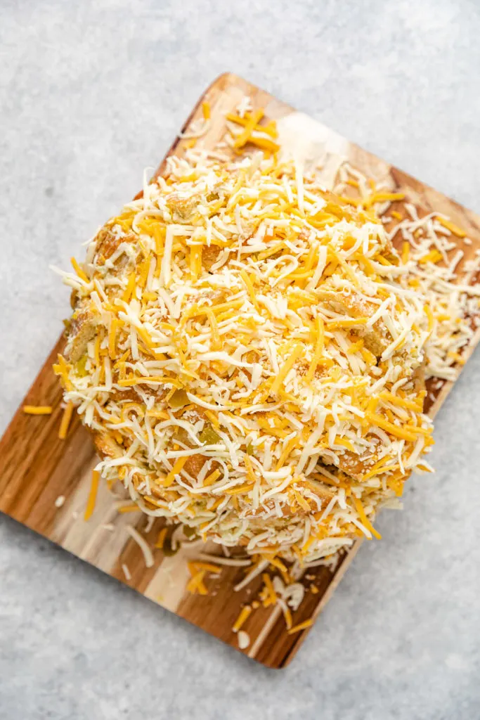 Shredded cheese on top of a loaf of bread.