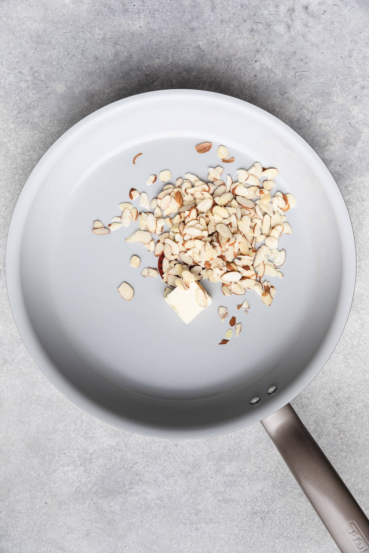 Top down view of almonds and butter in a pan.