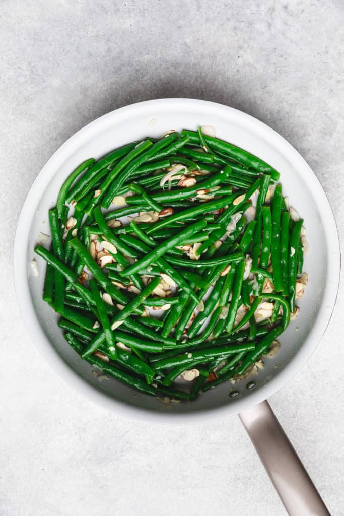 Top down view of green beans and almonds in a skillet.