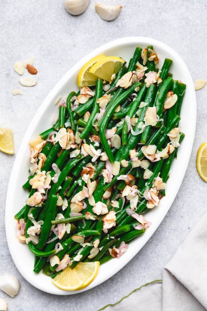 Oval dish filled with green beans and almonds.