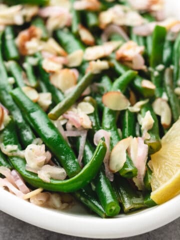 Close up of a plate of green beans with almonds.