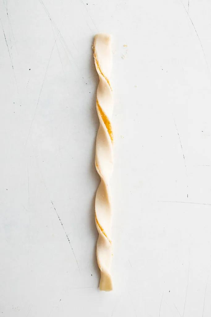 Unbaked cheese straw being twisted.