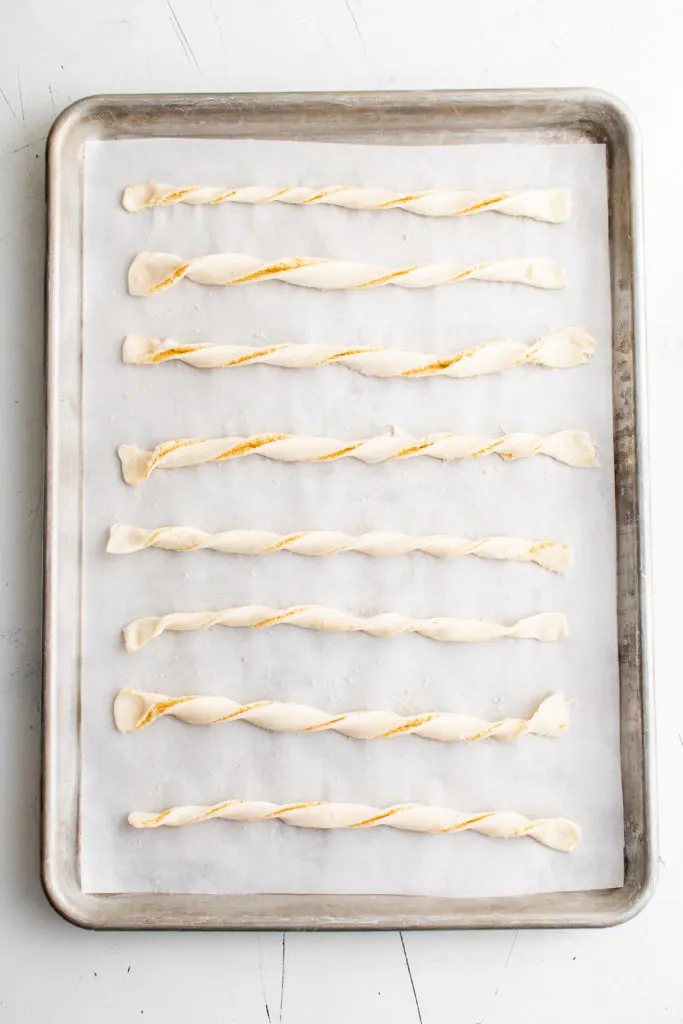 Unbaked cheese straws on a baking sheet.