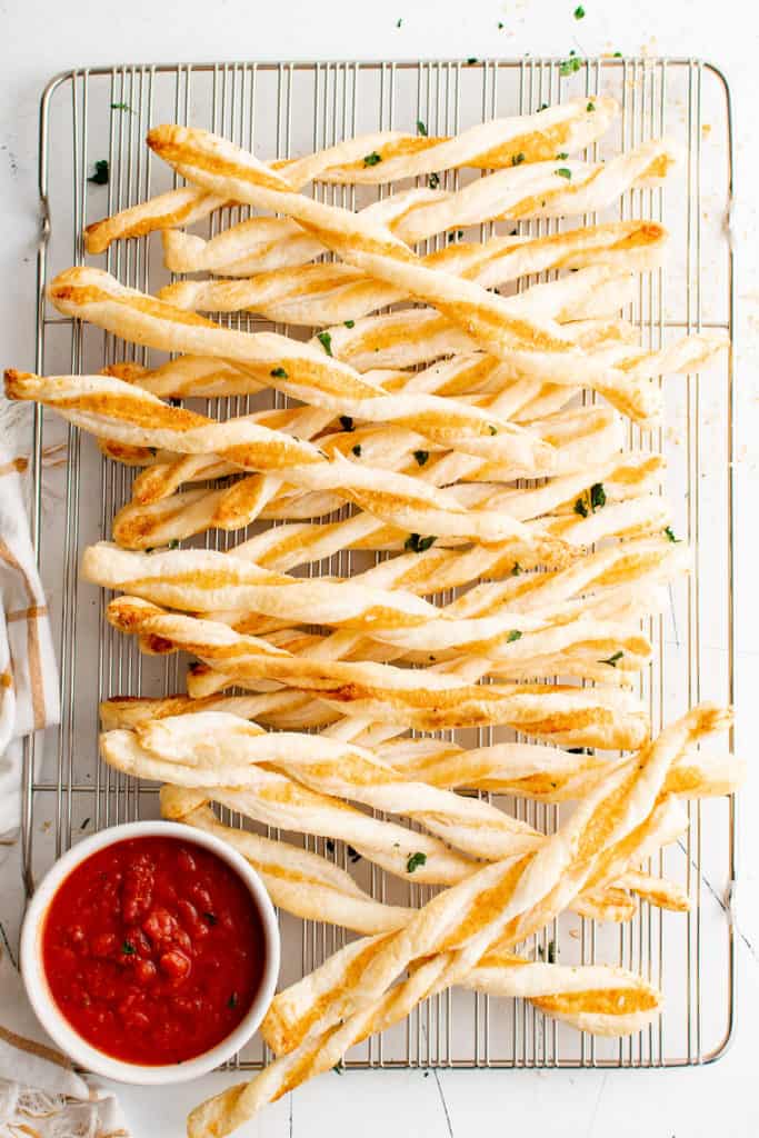 Puff pastry cheese straws on a wire rack.