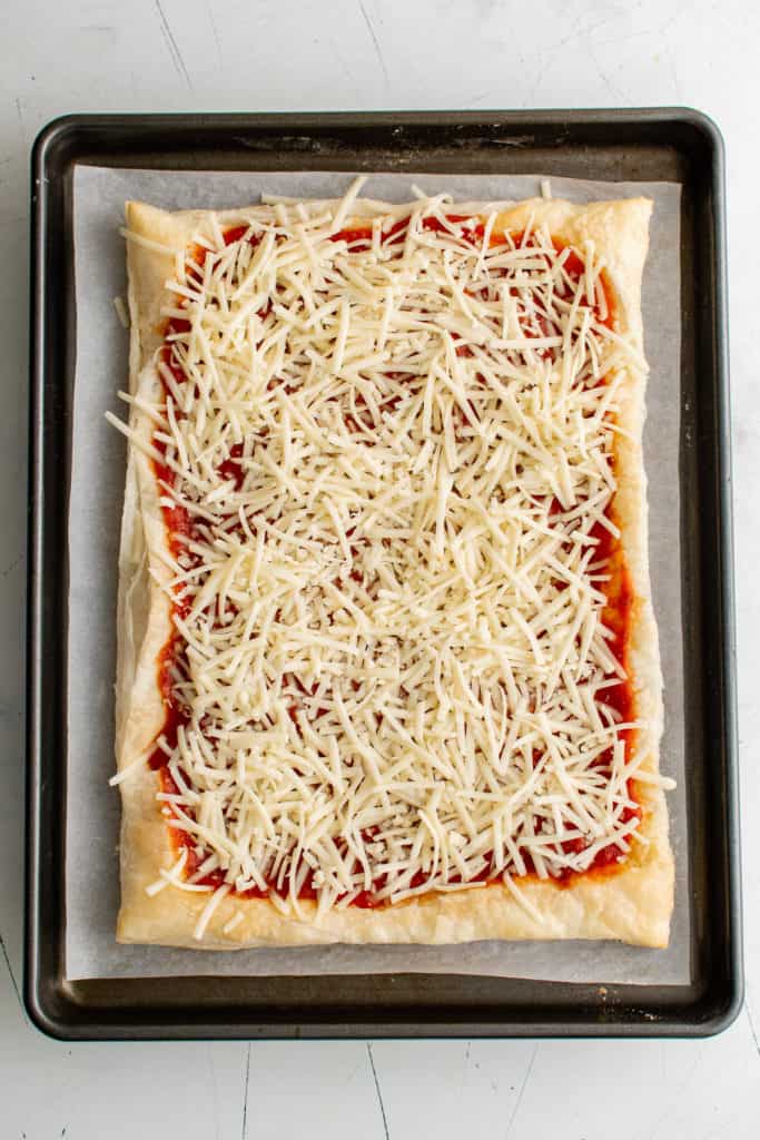 Shredded mozzarella cheese on puff pastry.