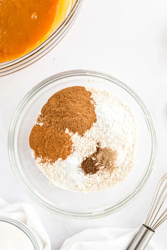 Flour, pumpkin pie spice, cinnamon, baking powder, salt, baking soda, cardamom, and cloves in a bowl.