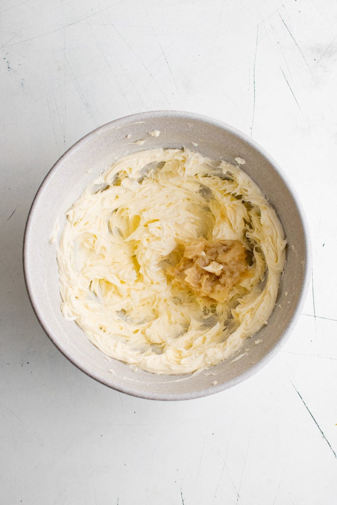 Top down view of mashed garlic in a bowl of butter.