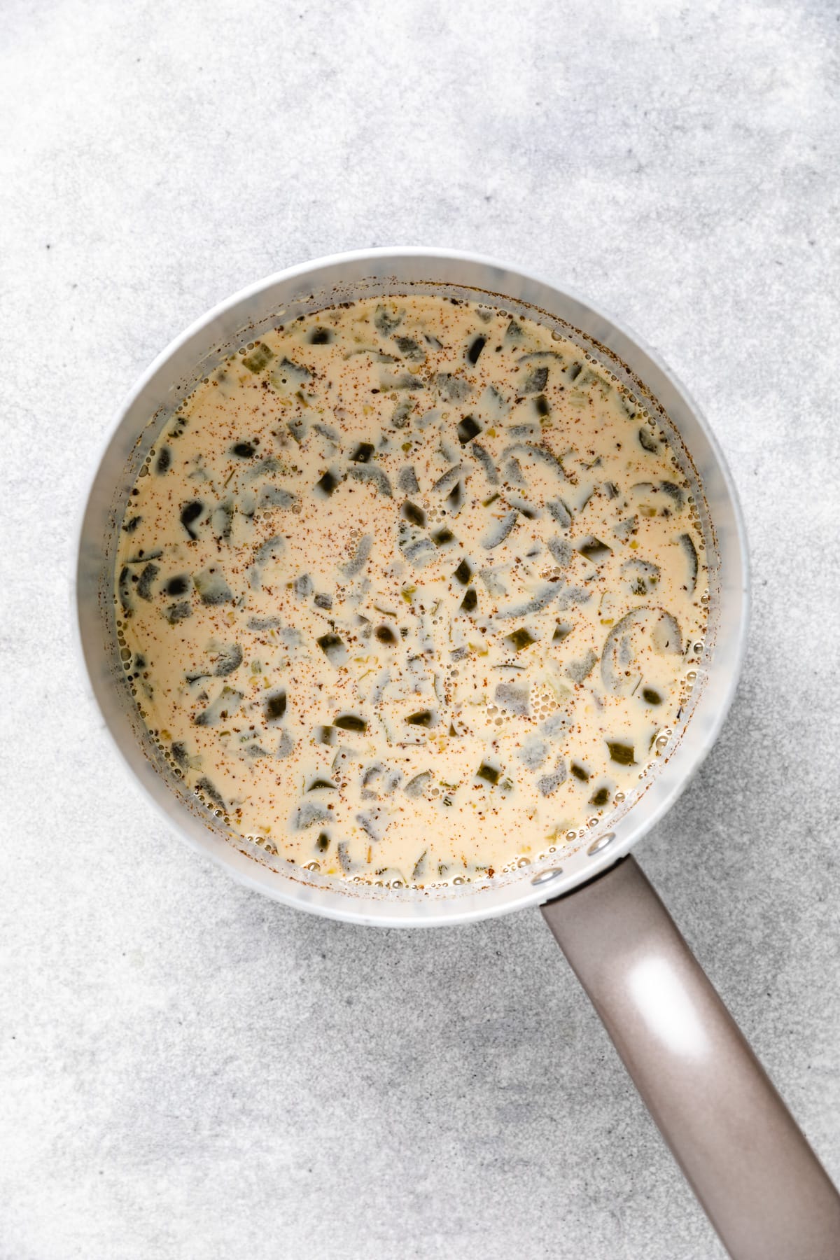 Green chiles, evaporated and seasonings in a pan.