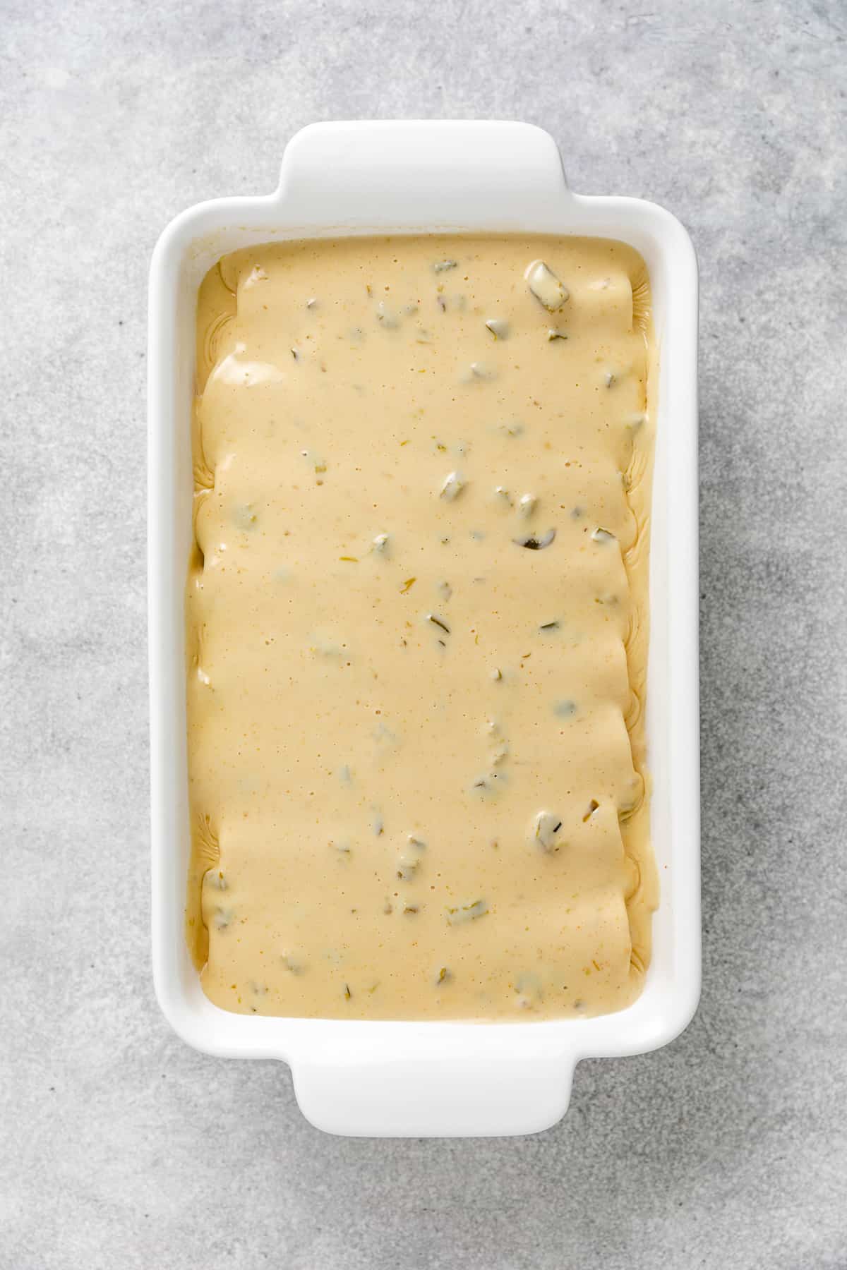Cheese sauce poured over enchiladas.
