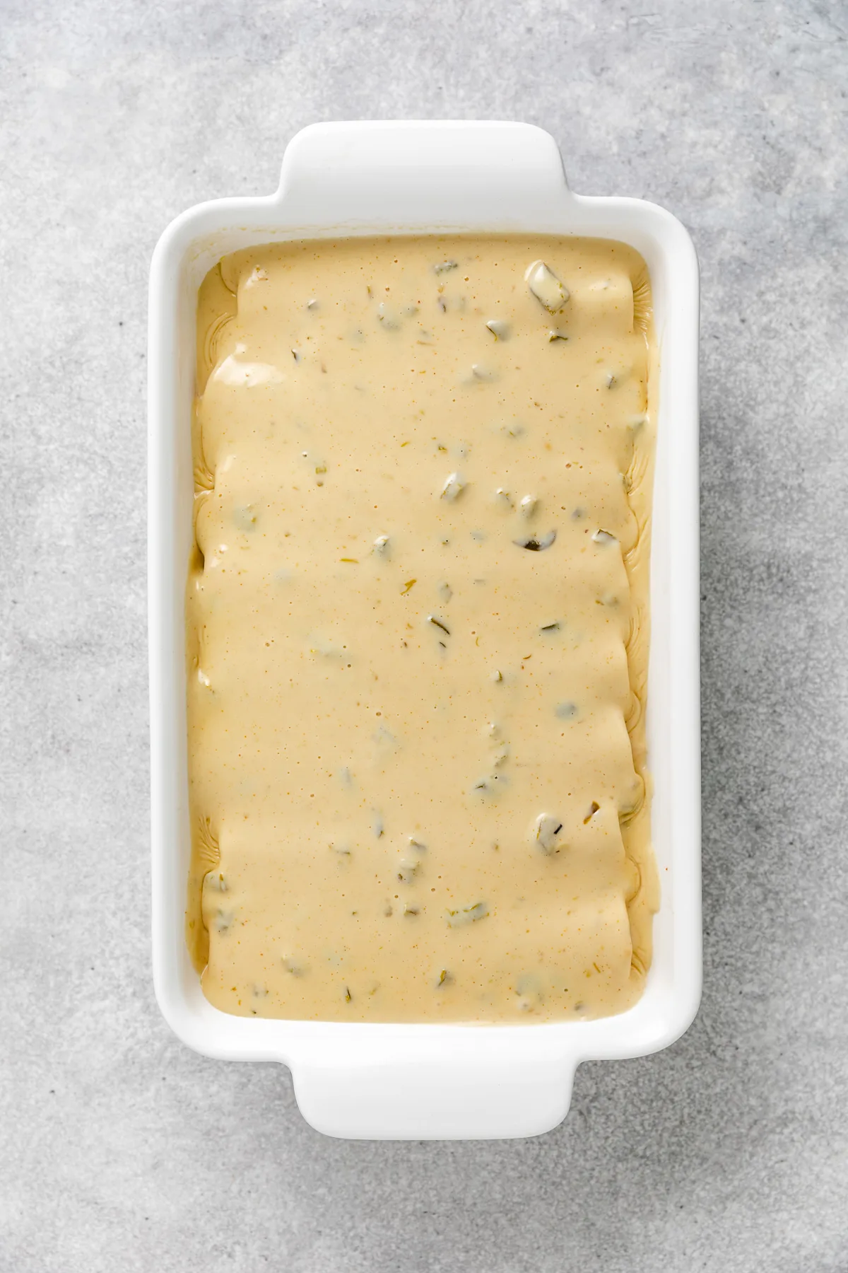 Cheese sauce poured over enchiladas.
