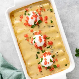 Top down view of cheesy beef enchiladas in a white dish.