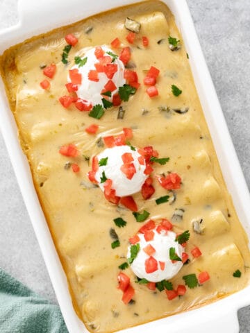Top down view of cheesy beef enchiladas in a white dish.