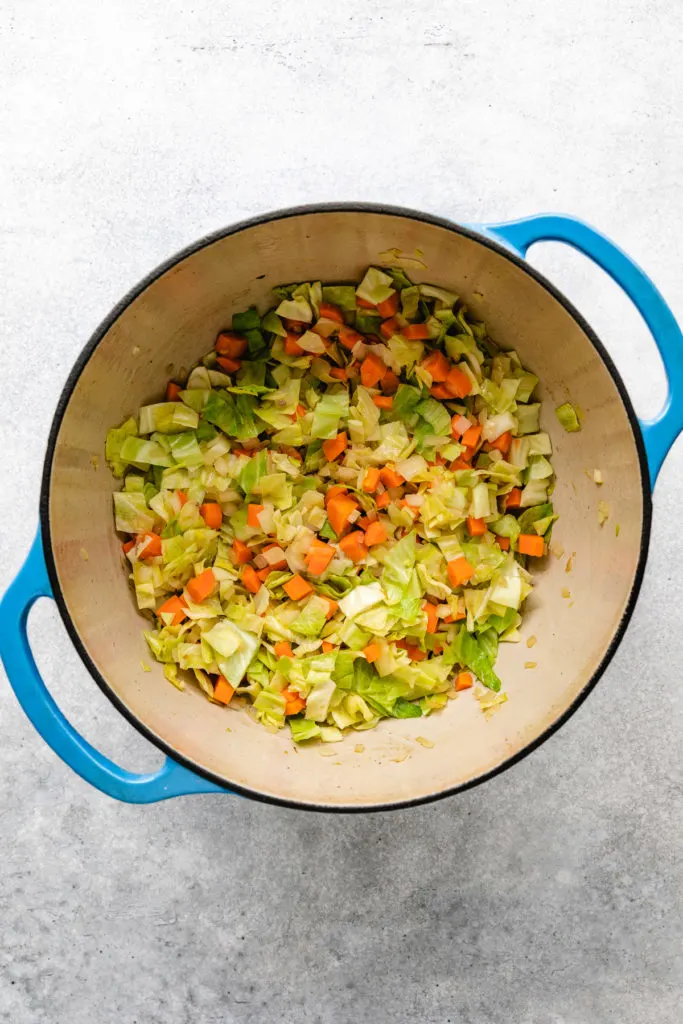 Sauteed cabbage, carrots and onions in a pan.