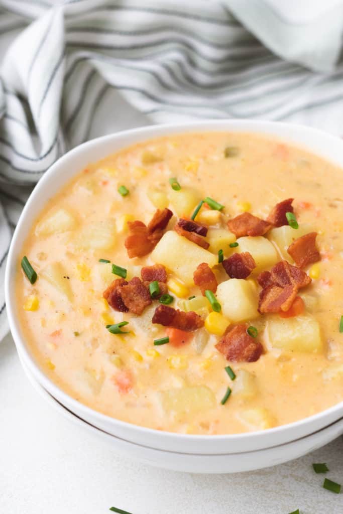 Bacon on top of a bowl of corn and potato chowder.