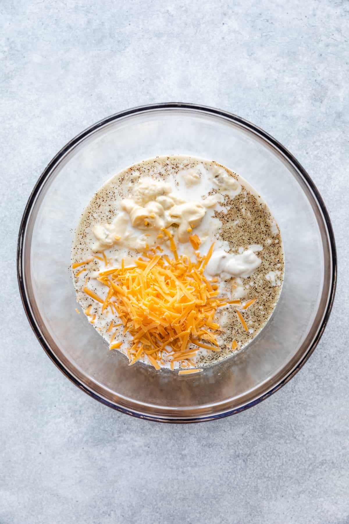 Milk, cheese seasonings, and canned soup in a bowl.