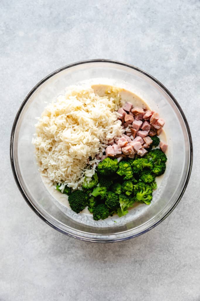 Broccoli, ham and rice on top of soup mixture in a bowl.