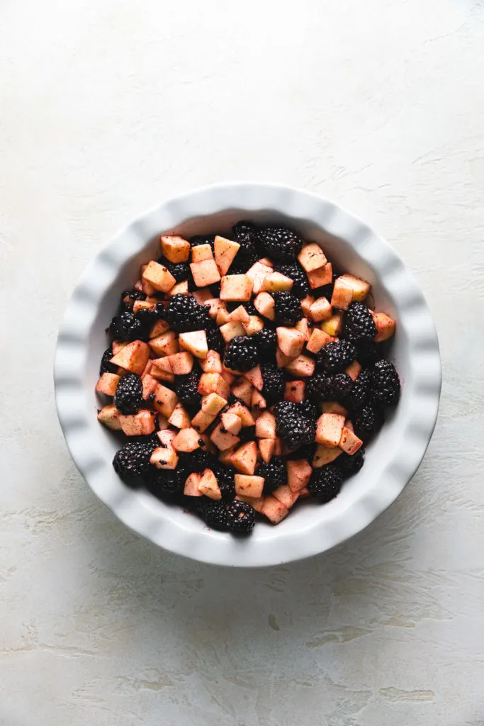 Top down view of apples and blackberries in a dish.