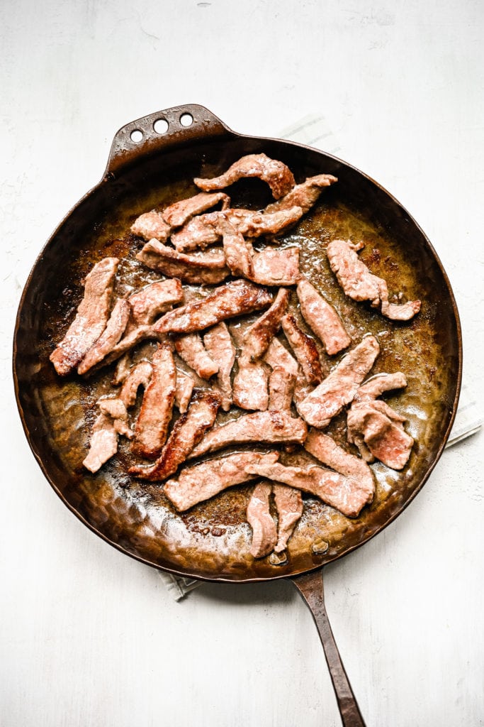 Thinly sliced beef sauteed in a pan.