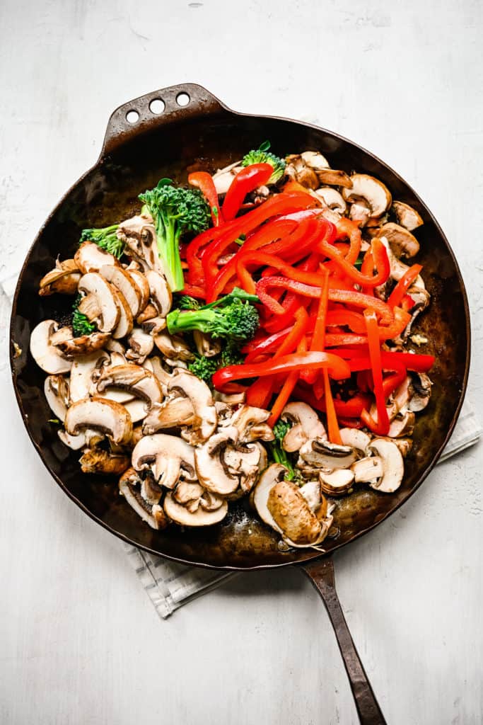 Peppers, broccoli, and mushrooms in a pan.