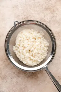 Rinsed rice in a mesh strainer.