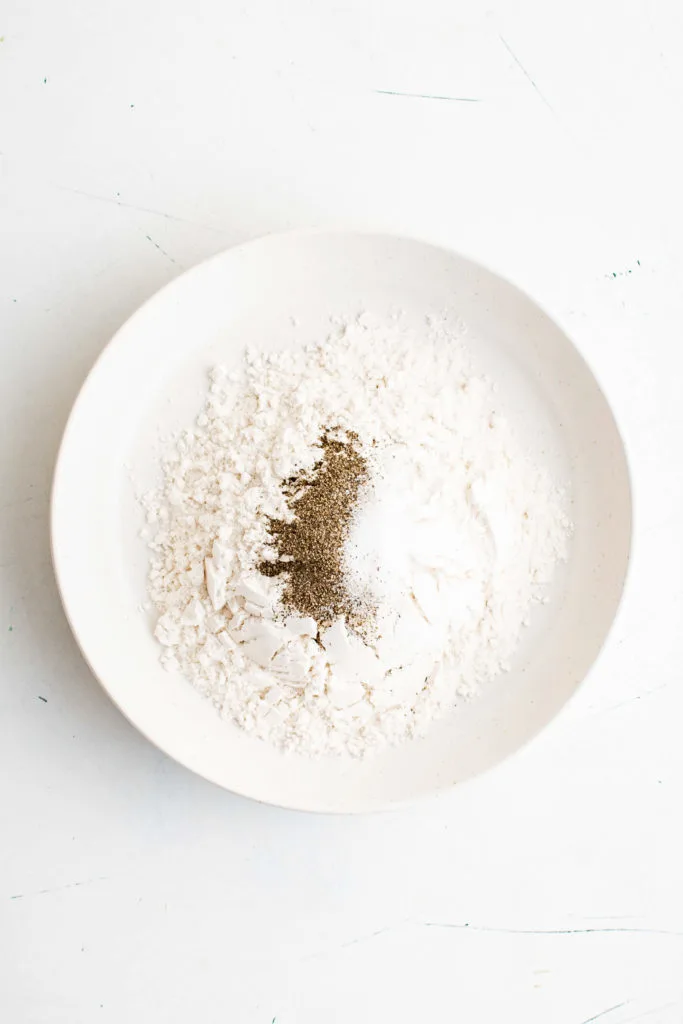 Salt and pepper adding to a dish of flour.