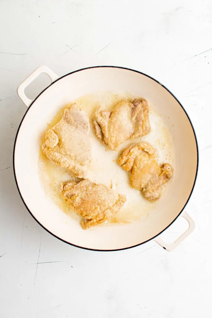 Chicken thighs cooking in a pan.