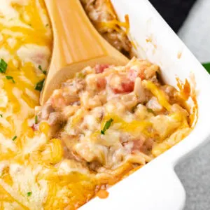 Close up view of a spoon scooping ground beef and rice casserole from a baking dish.