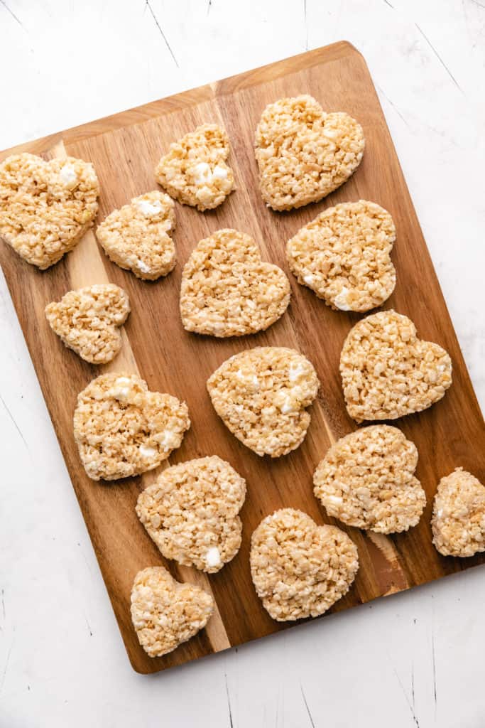 Top down view of heart shaped rice krispie treats on a cutting board.