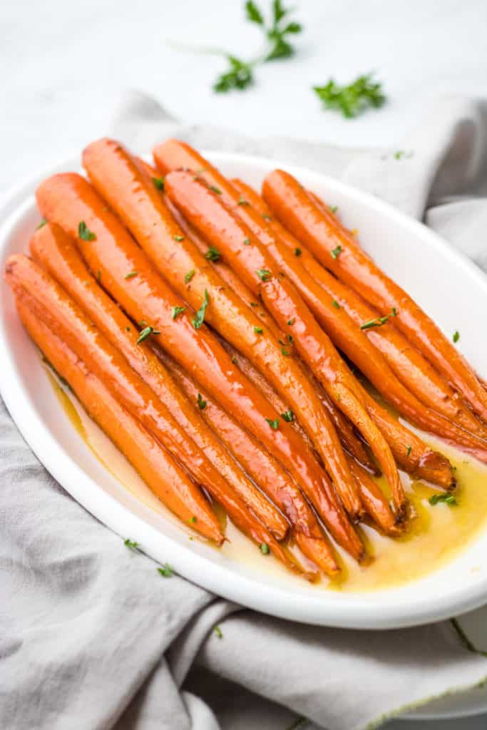 Side view of a white platter holding maple carrots.