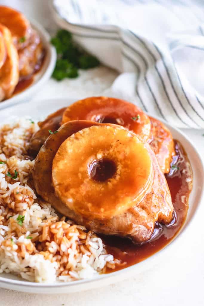 Side view of pork chops with brown sugar and pineapple on a plate.