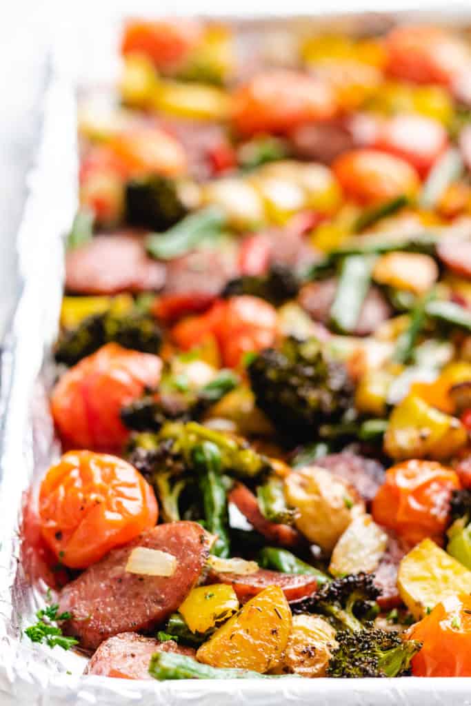 Side view of seasoned potatoes, peppers, sausage and onions on a pan.