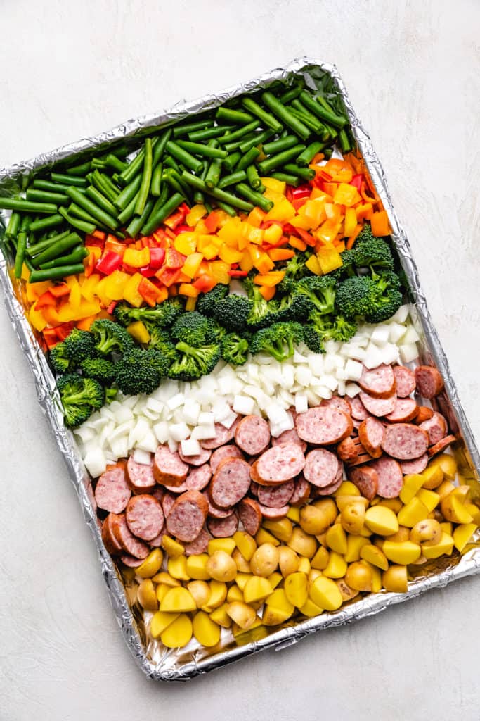 Top down view of chopped vegetables and sliced sausage on a pan.