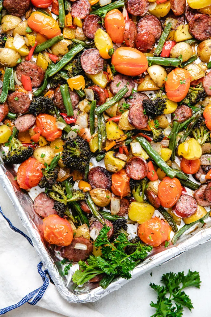 Close up view of parsley added to a pan of roasted veggies.