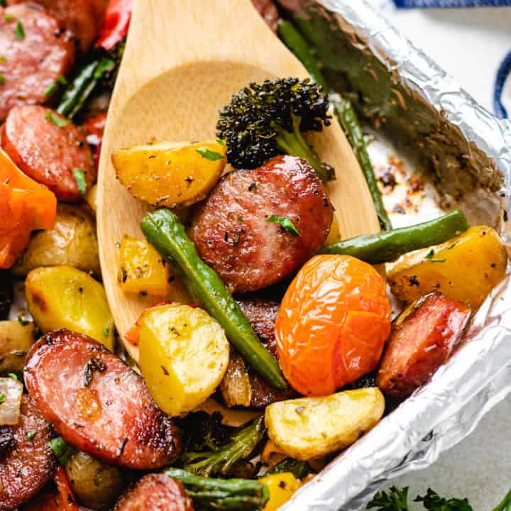 Close up view of sausage and veggies on a sheet pan.