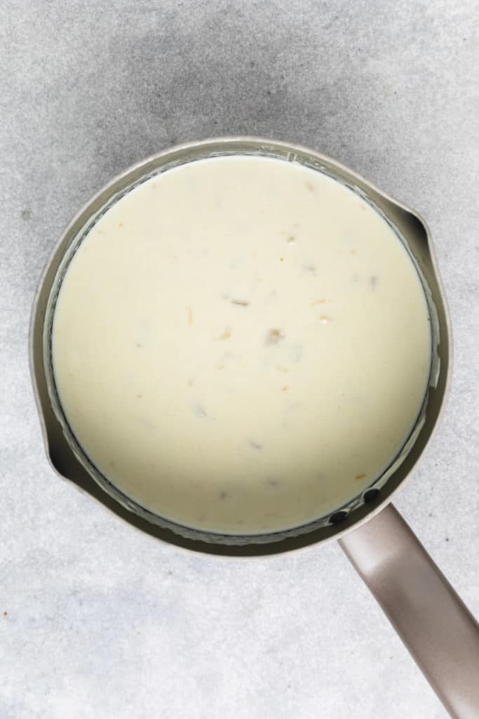 Top down view of white enchilada sauce in a pan.