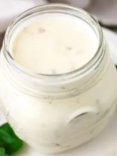 Close up view of a jar of green chile sour cream sauce.