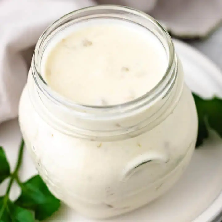 Close up view of a jar of green chile sour cream sauce.